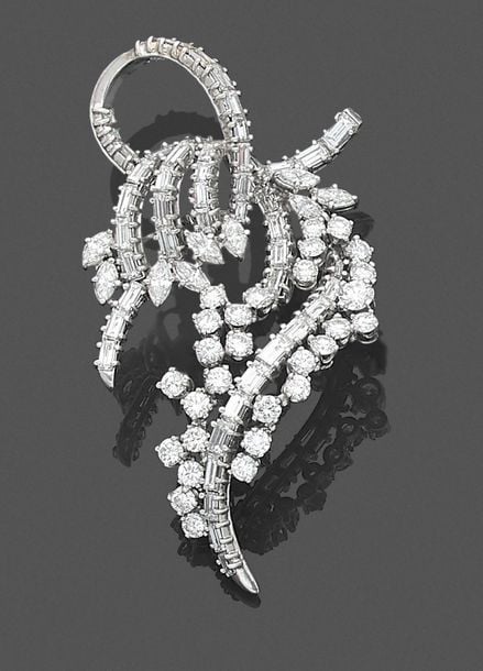 •BROCHE «volute» en or gris (750‰) ajouré serti de diamants taille brillant, baguettes et navette