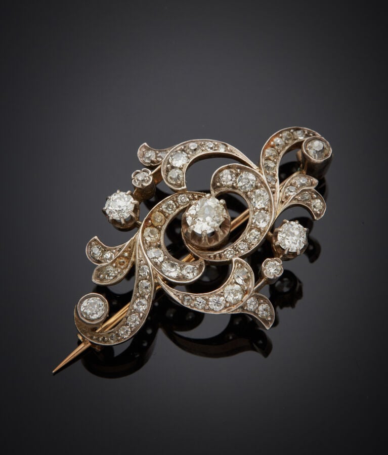 BROCHE "volutes" en or jaune (750‰) et argent (min. 800‰) ajouré, serti de diam…