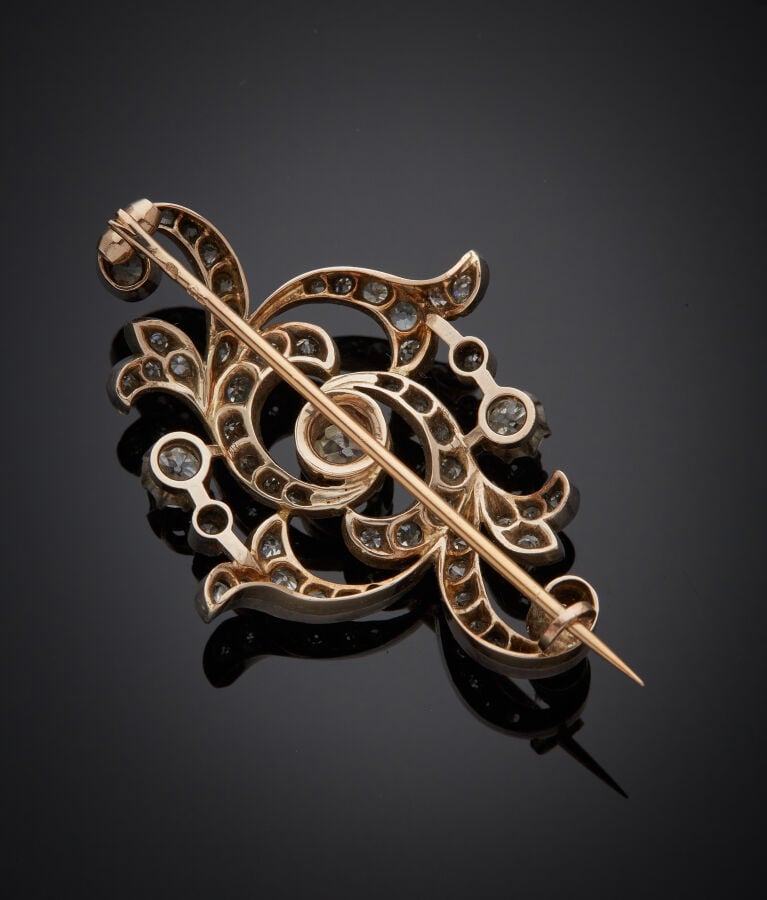 BROCHE "volutes" en or jaune (750‰) et argent (min. 800‰) ajouré, serti de diam…