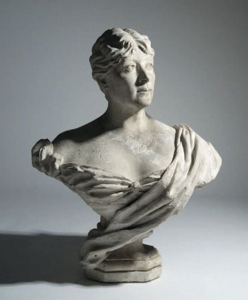Buste en plâtre représentant une femme de qualité, la tête légèrement tournée vers la gauche et portant une broche à son corsage; elle repose sur un piédouche hexagonal moulur