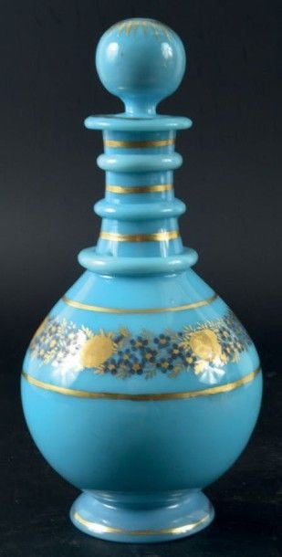 Carafe à piédouche et trois cordons de col en opaline de cristal turquoise à décor de filets dorés encadrant une guirlande de myosotis bleus et de fleurs dorées brunies à l'effet; bouchon boule à décor doré rayonnan