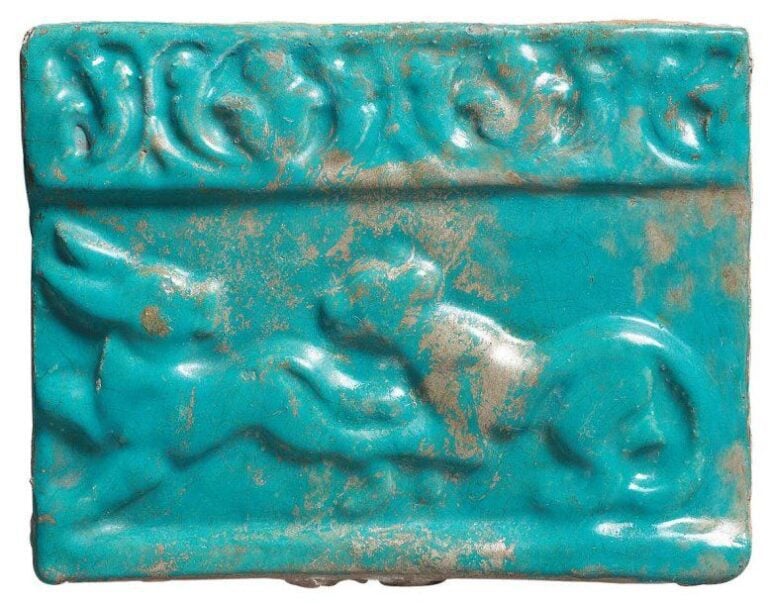 CARREAU À LA SCÈNE DE CHASSE Carreau de revêtement rectangulaire, à décor moulé sous glaçure turquoise, bordé d'une frise de fleurons trilobés et représentant une lionne poursuivant un lièvr