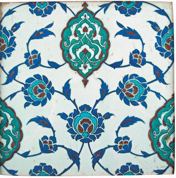 CARREAU AUX FLEURS ET « SAZ » Grand carreau de revêtement, décoré en polychromie et engobe rouge sur fond blanc de médaillons polylobés verts ornés de fleurons trilobés et palmettes parmi de fines branches de fleurs et « saz » bleues et turquois