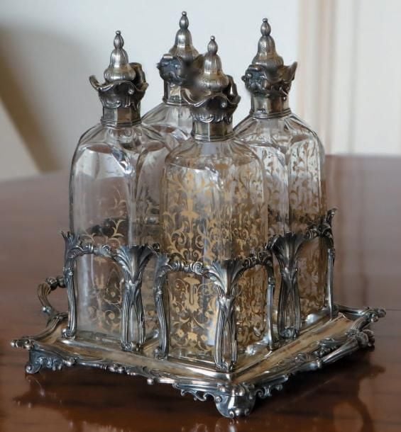 Cave à liqueur en métal argenté à décor feuillagé; elle présente quatre flacons de cristal partiellement dor