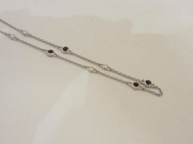 CHAINETTE en or gris (750 millièmes) à maille forçat alternée de saphirs noirs et diamants taille brillant en serti clo