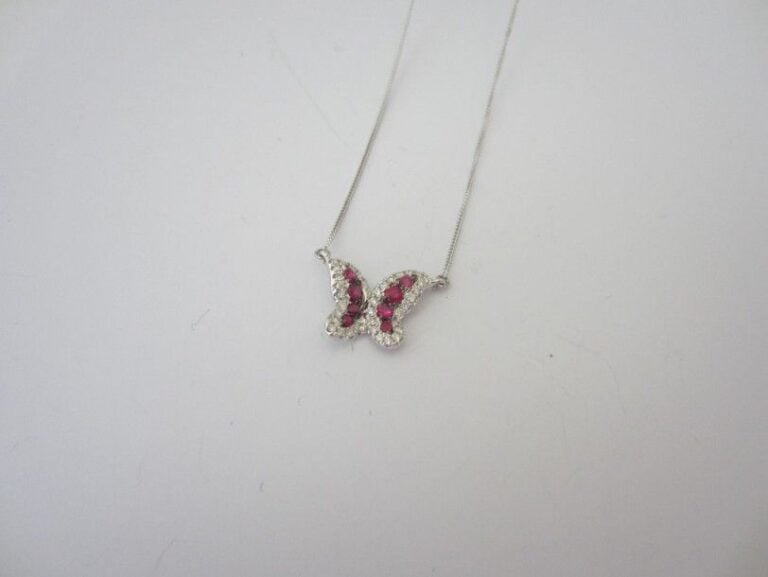 CHAINETTE en or gris (750 millièmes) retenant un «papillon» serti de rubis ronds et de diamants taille brillan