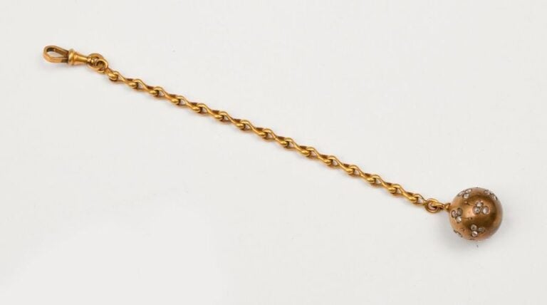 CHAINETTE ET PENDENTIF en forme de sphère en or jaune garni de deux trèfles stylisés sertis de diamants taillés en ros