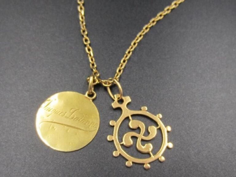 CHAÎNETTE retenant deux PENDENTIFS en or jaune (750 millièmes): une «croix basque» et une médaille de naissance gravée et datée «25 mars 1924