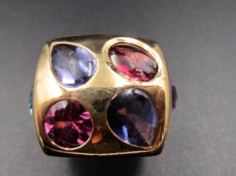 CHANEL      Large BAGUE chevalière en or jaune (750 millièmes) serti d’améthyste, topaze bleue, tourmaline rose, tanzanite, iolite et grenat suifés de forme ronde, poire et ovale        Egrisures et chocs        Signée CHANEL             Doigt : 50        Poids brut : 16,4 g