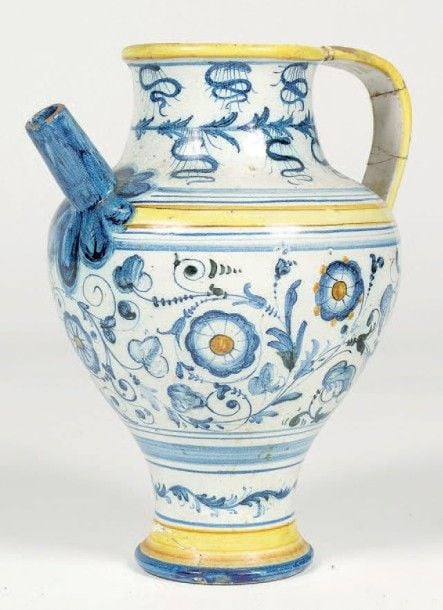 Chevrette en faïence à décor de rinceaux fleuris et feuillagés bleus sur fond blanc ; anse nervurée; déversoir cylindrique (restaurations