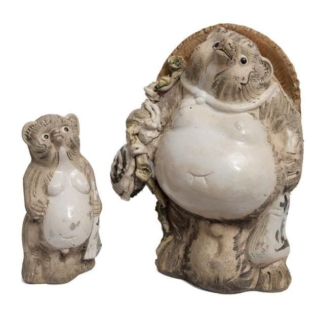 Chien viverrin (tanuki) portant une bouteille et un chapeau de paill