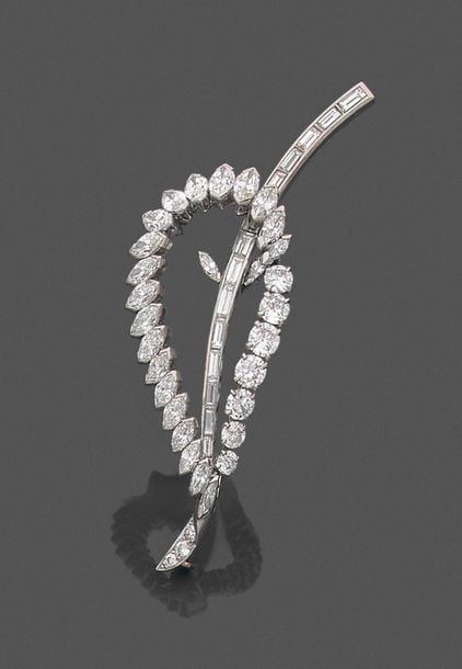 •CLIP DE CORSAGE «feuille stylisée» en platine (950‰) et or gris (750‰) ajouré serti de diamants taillé brillant, navette et baguett