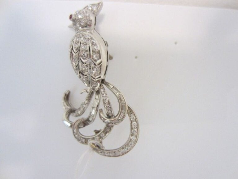 CLIP DE CORSAGE "oiseau de paradis" en platine (900 millièmes) et or gris (750 millièmes) serti de diamants ronds et baguettes, et d?un petit rubis cabocho