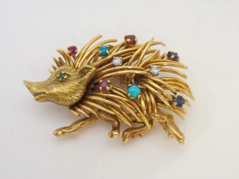 CLIP DE CORSAGE « porc-épic » en or jaune (750 millièmes) ciselé et ajouré serti de cabochons de turquoises, émeraudes, rubis, saphirs et diamants taille brillan