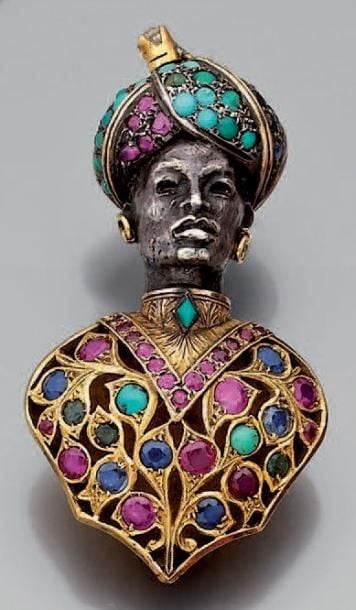 CLIP DE CORSAGE «tête de maure» en or et argent ajouré, ciselé, et serti de turquoises cabochons, rubis, saphirs et émeraude