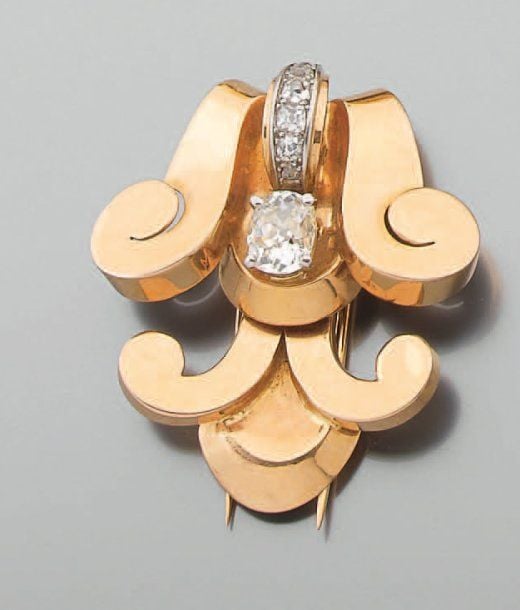 CLIP DE CORSAGE « volutes » en platine et or jaune serti de diamants de taille ancienne dont un de forme coussin plus importan