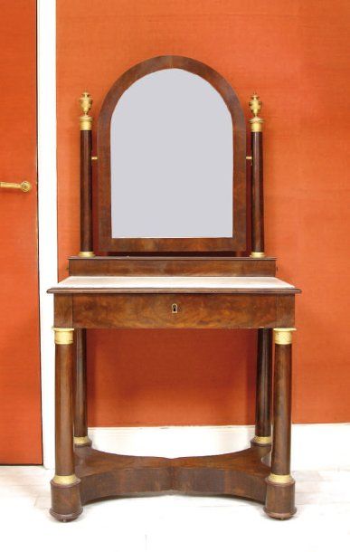Coiffeuse en acajou et placage d'acajou, présentant sur un entablement encastré de marbre blanc, un miroir à arc en fronton, soutenu par deux colonnes latérale