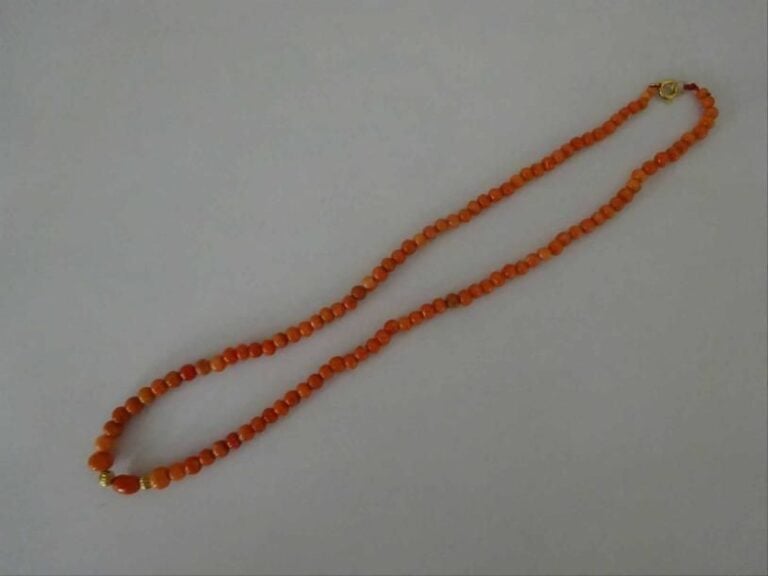 COLLIER AUX PERLES DE CORAIL ROUGE ORANGE Chine, Epoque XXe siècle Fermoir métal doré, perle centrale oblongue flanquée de deux boules godronnées en également en métal dor