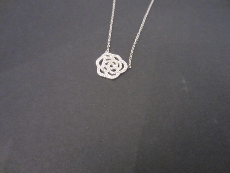 COLLIER chaînette en or gris (750 millièmes) retenant une «fleur» ajouré et serti de petits diamants taille brillant
