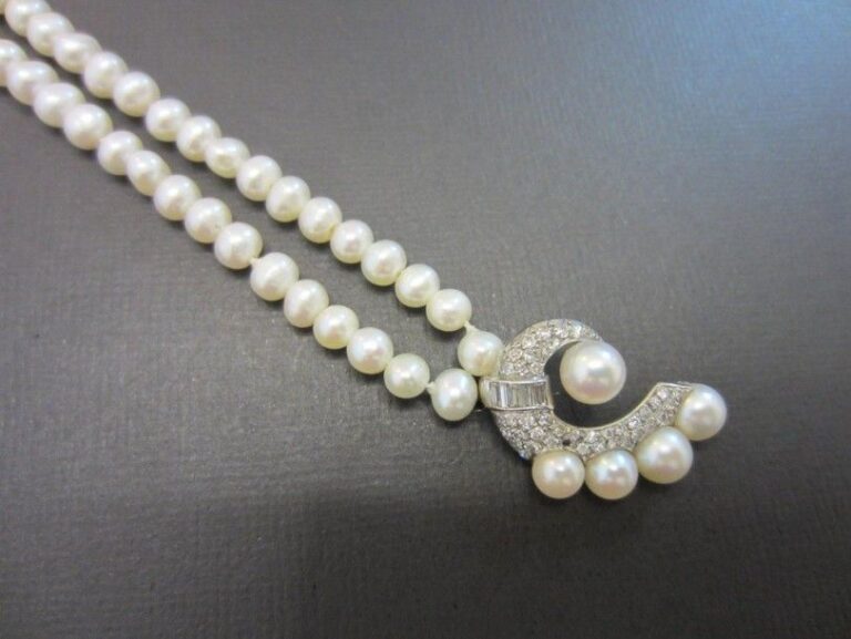 COLLIER composé d'un rang de perles de culture blanches légèrement baroques retenant un motif «volute» en platine serti de diamants 8/8 et baguettes et orné de 5 perles de culture blanche