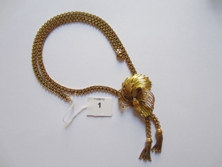 COLLIER composé d'une chaîne plate en or jaune articulé retenant deux pompons de floches d'or et surmonté d'un motif «volutes et feuille» serti de pierres blanche
