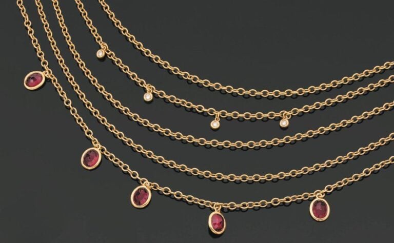COLLIER composé de cinq chaînettes en or jaune retenant grenats ovales et diamants en serti clo