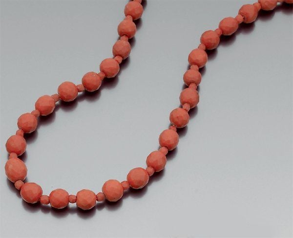 COLLIER composé de perles de corail facettées de tailles différentes alternées, en chut