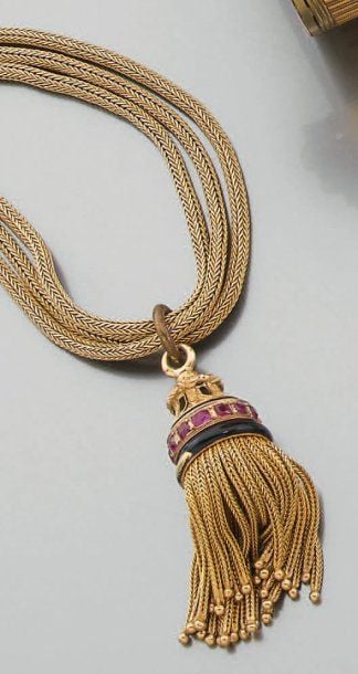 COLLIER composé de trois chaînes « colonne » en or jaune retenant un pompon en or partiellement émaillé (manques à l'émail) et serti de pierres rouge