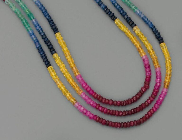 COLLIER composé de trois rangs de rubis, émeraudes et saphirs, facettés et alterné