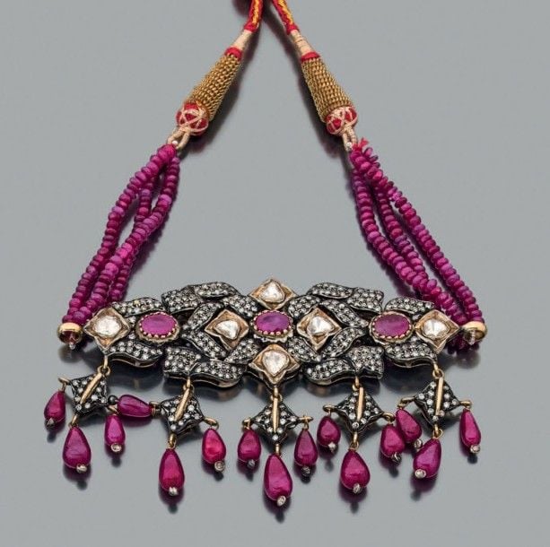 COLLIER DE CHIEN composé de trois rangs de perles de rubis retenant un motif «Galpati» en or jaune (750 millièmes) et argent (mi