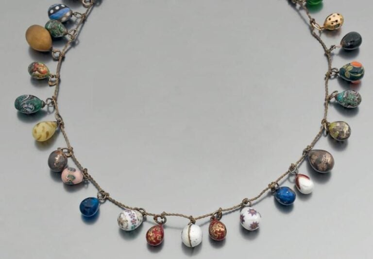 COLLIER de fils retenant une variété d'oeufs russes en verre, céramique, or, argent et métal partiellement émaillés et ciselés ou serti