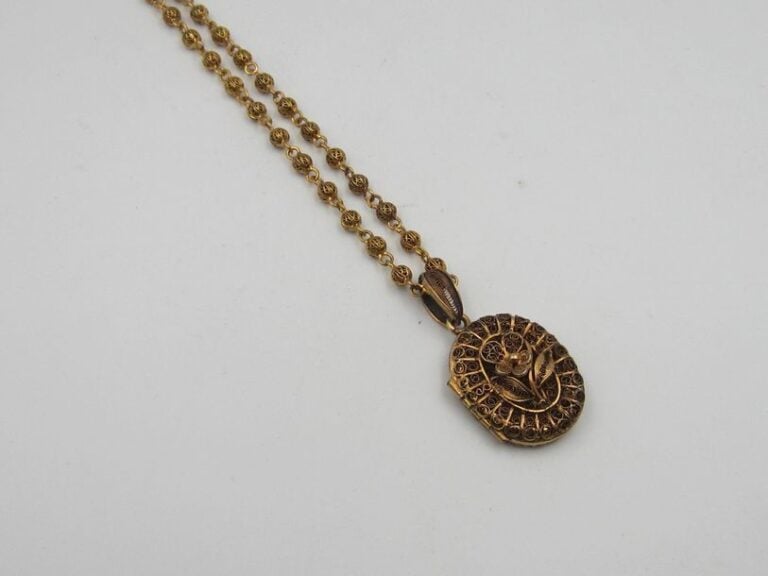COLLIER en métal doré à motif de boules travaillées ajourées retenant un médaillon ouvrant à décor d'une pensée