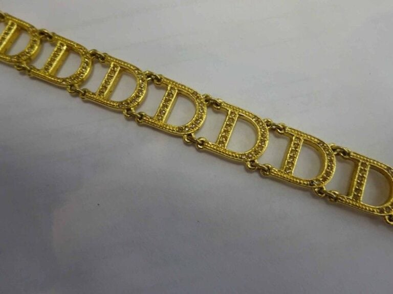 Collier en métal doré les mailles articulées formant D fermoir aux initiales de la Maison (CD