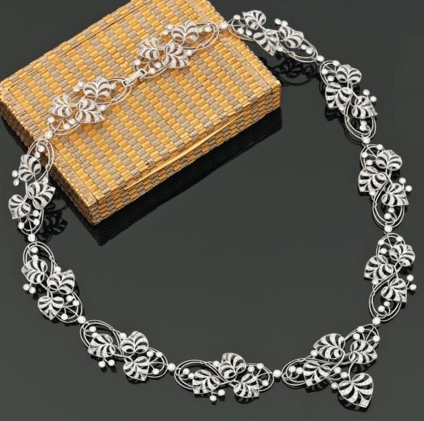 COLLIER en or gris ajouré serti de diamants taille brillant, à motifs de feuilles et volute