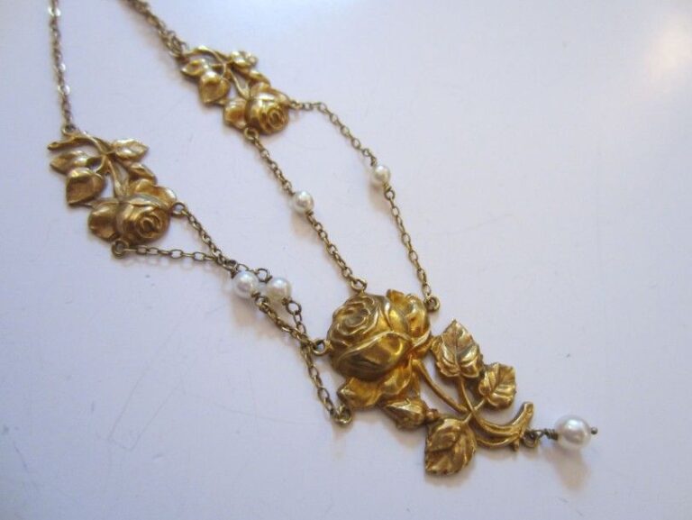 COLLIER en or jaune composé d'une chaînette retenant trois motifs de fleurs ciselées et cinq perles de culture dont une en pampill