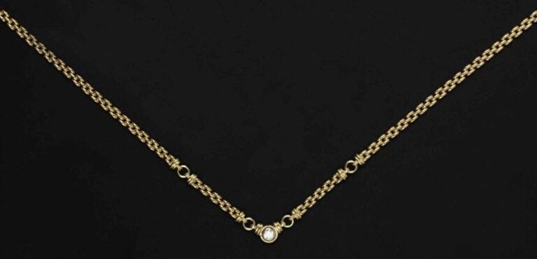 COLLIER en or jaune et or blanc 18K (750°/00) à maillons bombés articulés de cercles et de godrons retenant au centre un diamant taille brillant en serti clos d'environ 0 45 cara