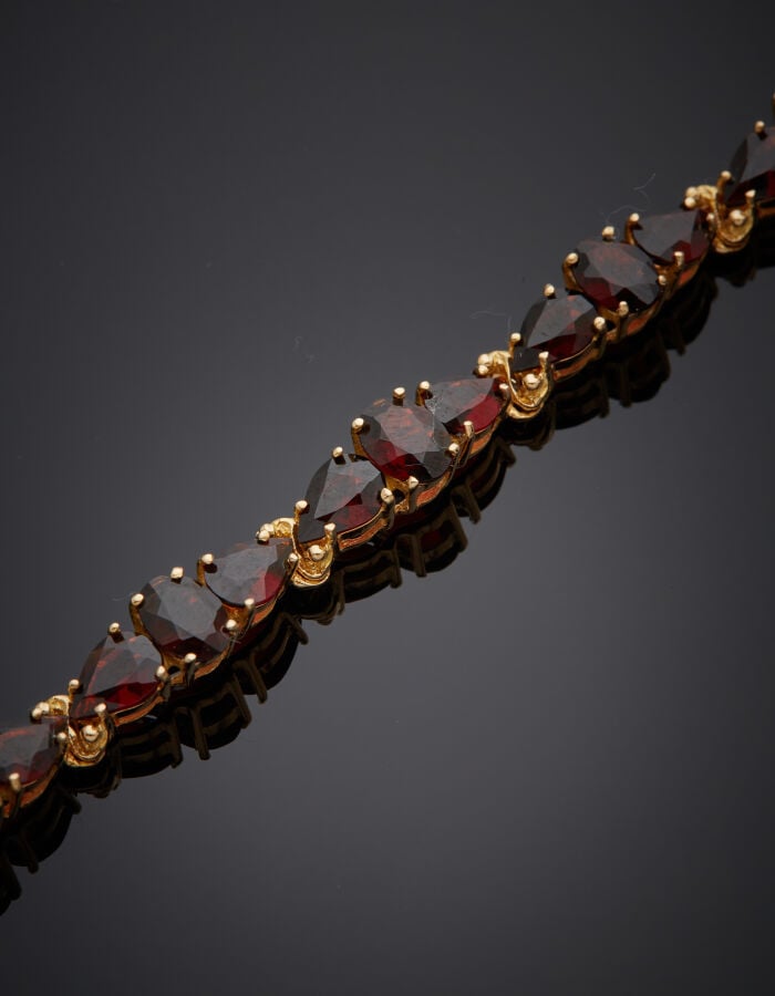 COLLIER et BRACELET en or jaune (750‰) serti de grenats de forme navette, ronde…