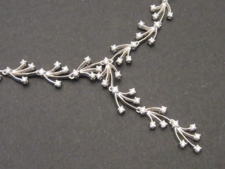 COLLIER «feuilles stylisées» en or gris (750 millièmes) articulé partiellement serti de diamants taille brillant, dont quatre motifs retenus en pendan