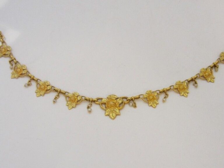 COLLIER « fleurettes » en or jaune (750 millièmes) retenant neuf motifs ciselés et ajourés séparés par de petites perles probablement fines en pampill