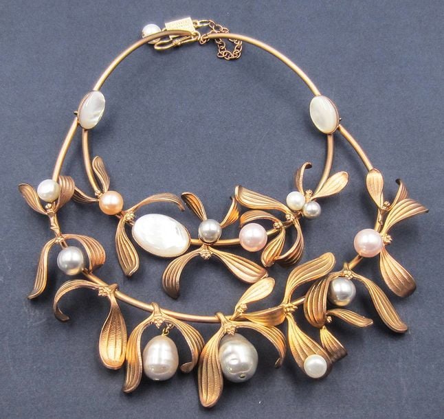 Collier semi rigide en métal doré orné de perles grises, blanches et roses, formant des fleurs de gu