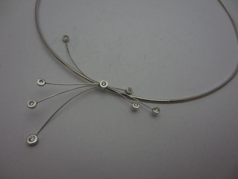 COLLIER souple en or gris (750 millièmes) retenant un motif «rayonnant » orné de diamants taille brillant en serti clo