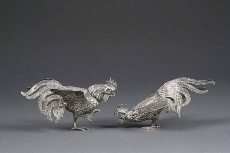 COMBAT DE COQS EN ARGENT Egypte, Epoque XXe siècle, Périod République Les deux volatiles saisis dans leur lutte, les ailes déployées, l'un prenant le pas sur l'autre qui se penche en avan