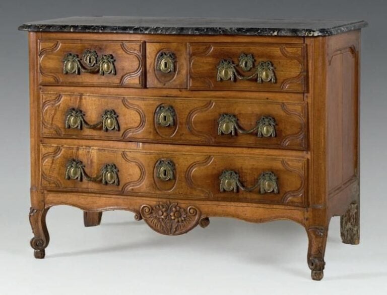Commode en noyer mouluré de forme légèrement arquée; elle ouvre par quatre tiroirs sur trois rang