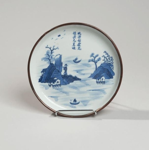 Coupe en porcelaine à décor en bleu sous couverte de maisons sur pilotis dans un paysage lacustr