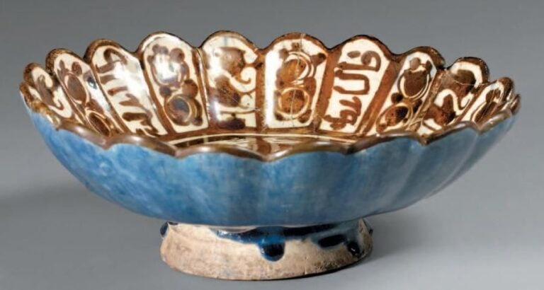 Coupe fragmentaire à la harpie Céramique à décor de lustre métallique Cette coupe polylobée porte sur le marli des cartouches en calligraphie coufique alternés de calligraphie cursive et de décors végétaux, au centre une harpie se détache en négatif sur un fond de lustr