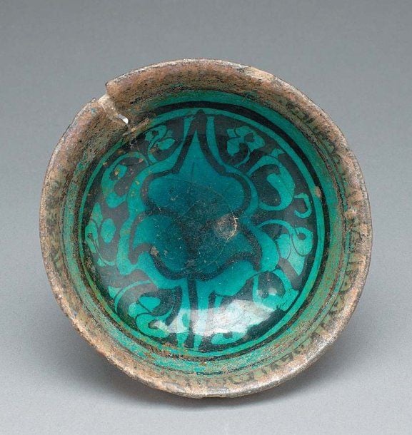 COUPELLE AYYOUBIDE Coupelle hémisphérique, décorée en noir sous glaçure turquoise d'un fleuron entouré de palmettes et d'une frise pseudo-coufique en bordur