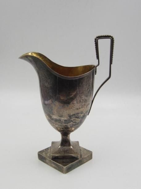 Crémier de forme casque en argent (minimum800 ‰) uni à piédouche carré reposant sur une base quadrangulaire; intérieur en vermeil; anse perlé