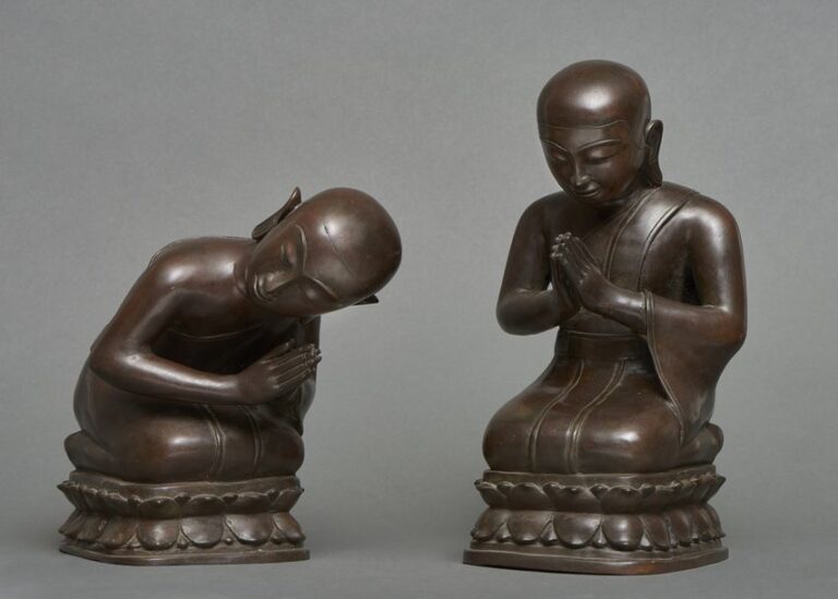 Deux lourde figurines en bronze foncé de jeunes moines bouddhistes en position inclinée de prièr