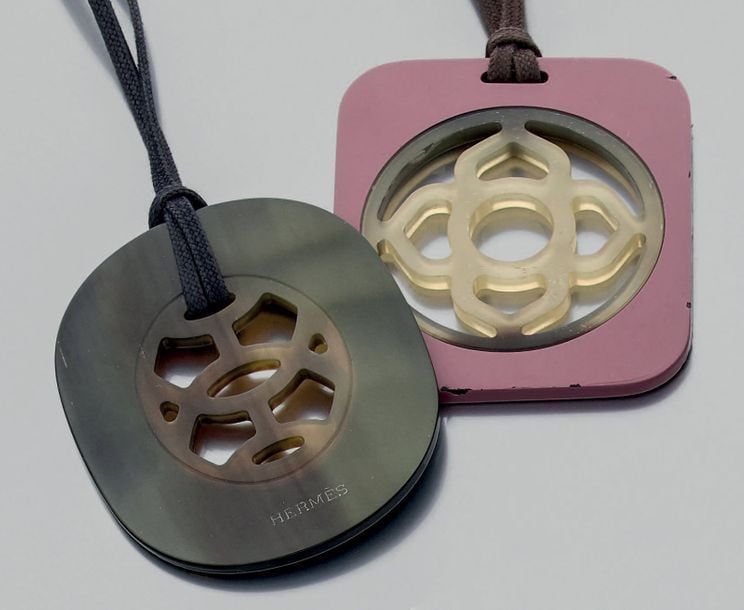 Deux PENDENTIFS «corne et laque», de couleur noire et vieux rose, ajourés, façon écaill