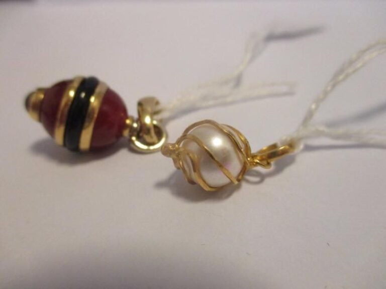 Deux pendentifs en or jaune 18K (750°/00), l'un serti d'une perle fantaisie, l'autre en verre ocre et noi